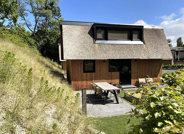 Frontansicht der 6-Personen-Duenenlodge Bosrand mit Ladestation in Schoorl, Nordholland, umgeben von Gruen.