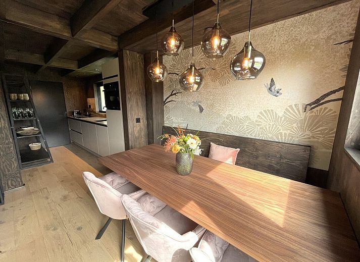 Terrasse der 6-Personen-Duinlodge Bosrand in Schoorl, Nordholland, mit Esstisch aus Holz und Blick auf die Natur.