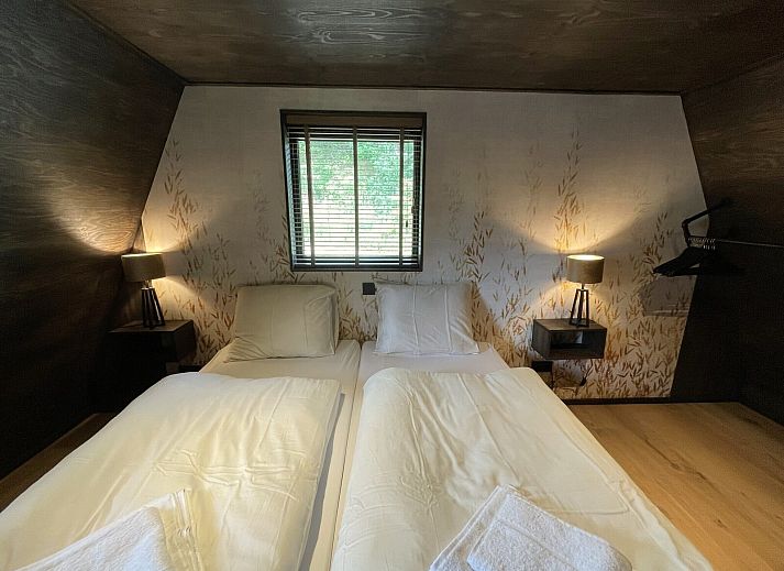Terrasse der 6-Personen-Duinlodge Bosrand in Schoorl, Nordholland, mit Esstisch aus Holz und Blick auf die Natur.
