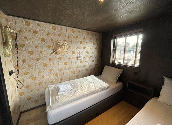 Seitenansicht des 6-Bett-Ferienhauses Duinlodge Bosrand in Schoorl, Nordholland, mit Garten und Sonnenschirm.