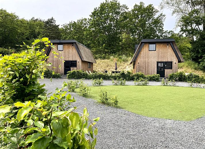 Seitenansicht des 6-Bett-Ferienhauses Duinlodge Bosrand in Schoorl, Nordholland, mit Garten und Sonnenschirm.