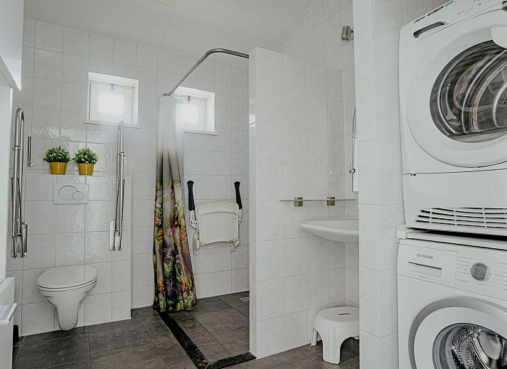 Helles Interieur des Ferienhauses Kraaijennest in Uitgeest mit grossen Fenstern und stilvollen Moebeln.