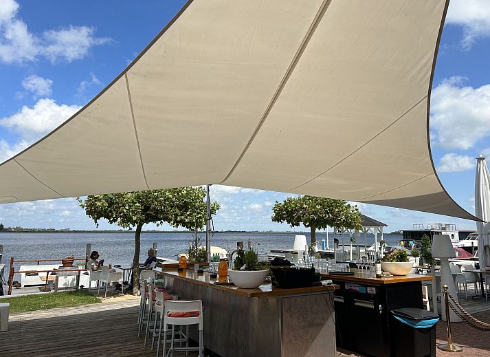 Eethoek en tv in Appartement Westergeest 2, Uitgeest, Noord-Holland, met warme inrichting en moderne voorzieningen.