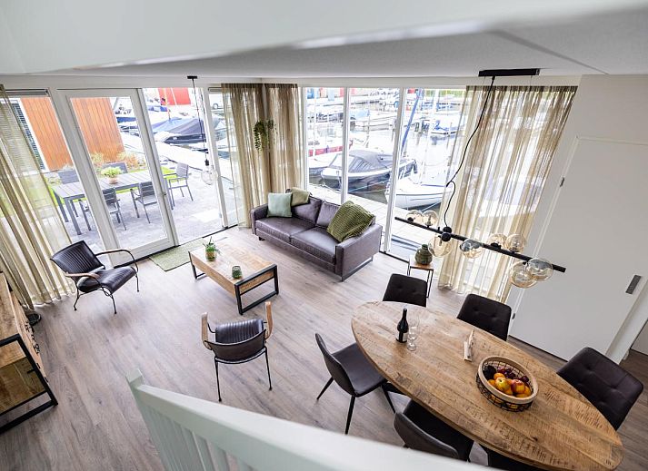 Geniessen Sie die Terrasse des Lakehouse I in Uitgeest, Nordholland, mit Blick auf den Yachthafen und den komfortablen Innenbereich dieses Ferienhauses.