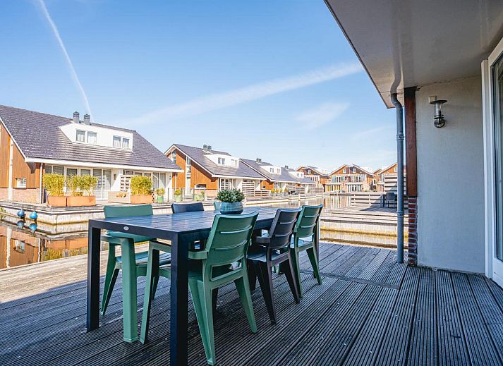 Gemuetliches Wohnzimmer im Ferienhaus Busch en Dam in Uitgeest, Nordholland, mit moderner Einrichtung und Blick auf den Garten.