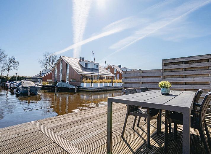 Gemuetliches Wohnzimmer im Ferienhaus Busch en Dam in Uitgeest, Nordholland, mit moderner Einrichtung und Blick auf den Garten.