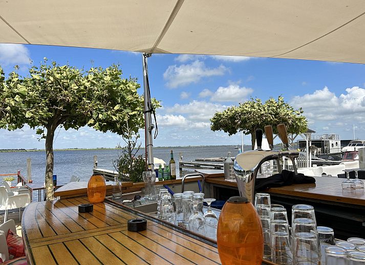 Terras met stuurwiel en uitzicht op de haven bij Vakantiehuis Havenlodge, Uitgeest, Noord-Holland.