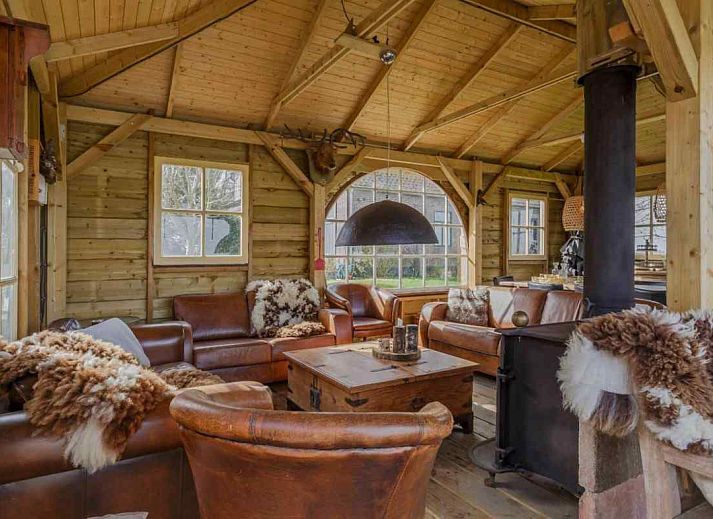 Buitenveranda van NH135 vakantiehuis in Schermerhorn, Noord-Holland, omgeven door groen.