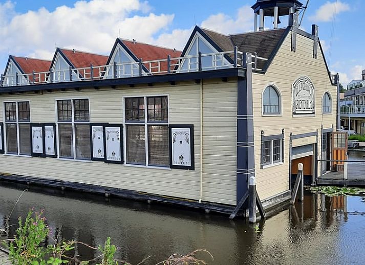 Gezellige veranda van Huisje in Zuid-Scharwoude, een vakantiehuis in Noord-Holland, met uitzicht op de groene omgeving.
