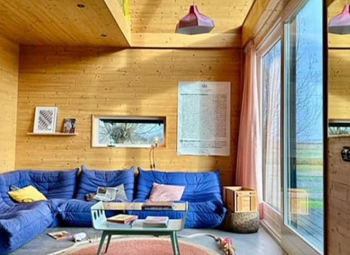 Gezellige woonkamer van Huisje in Oostknollendam, vakantiehuis in Noord-Holland met uitzicht op groene velden.