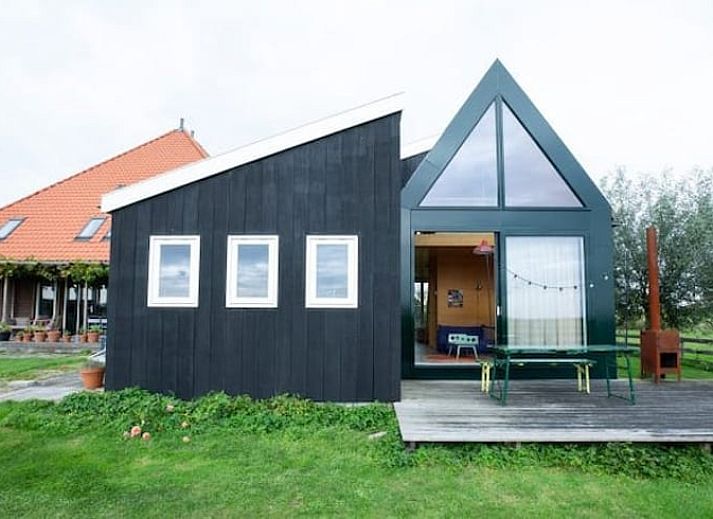 Gezellige woonkamer van Huisje in Oostknollendam, vakantiehuis in Noord-Holland met uitzicht op groene velden.