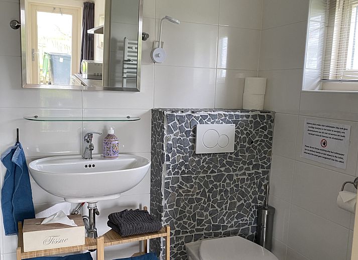 Sonnenterrasse des Ferienhauses NH539 in Spanbroek, Nordholland mit Blumen und Sitzgelegenheit