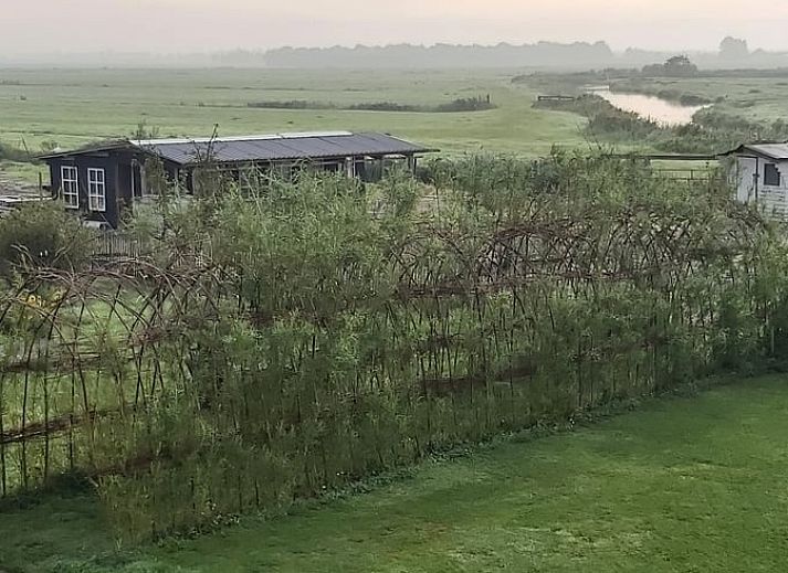 Comfortabele slaapkamer in Vakantiehuisje in Markenbinnen, Noord-Holland, met kleurrijke accenten en toegang tot balkon.