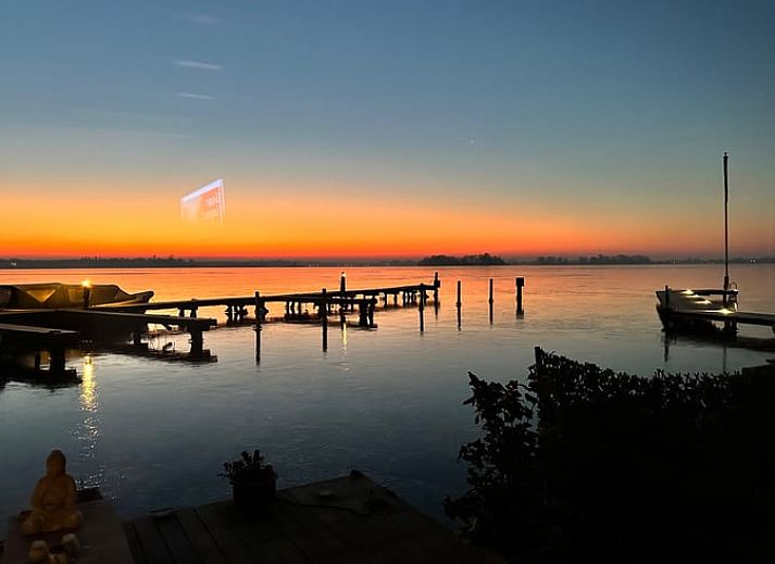 Gemuetliche Terrasse im Ferienhaus in Loosdrecht, Nordholland, mit Blick auf das Wasser und einem komfortablen Sitzbereich.