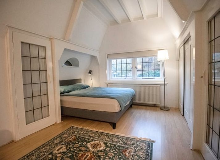 Zijaanzicht van vakantiehuisje in Naarden, Noord-Holland zuid, met karakteristiek rieten dak en groene omgeving.