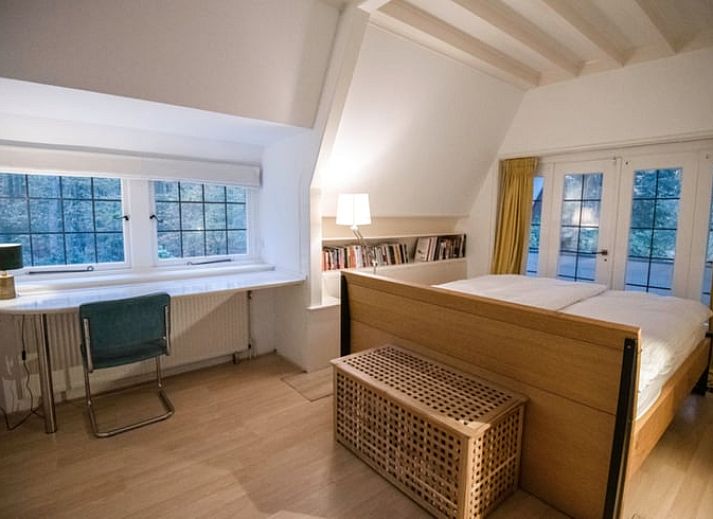 Zijaanzicht van vakantiehuisje in Naarden, Noord-Holland zuid, met karakteristiek rieten dak en groene omgeving.