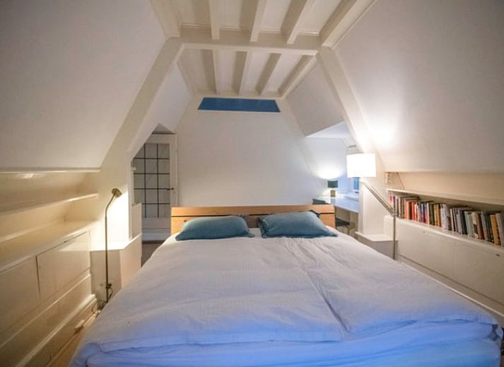 Zijaanzicht van vakantiehuisje in Naarden, Noord-Holland zuid, met karakteristiek rieten dak en groene omgeving.