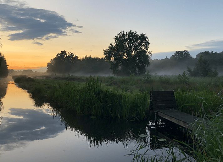 Rustic terrace at cottage in Kortenhoef, North Holland, overlooking green surroundings.