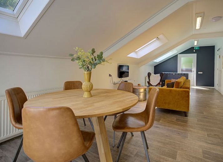 Gemuetliches Wohnzimmer im Ferienhaus in de Lutte, Twente, mit buntem Sofa, Holzofen und grossem Esstisch fuer einen komfortablen Aufenthalt.