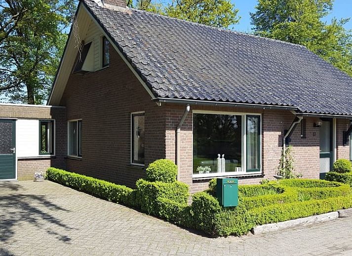 Dining room with wooden table and chairs in vacation home Hezingen, Twente, with garden view.
