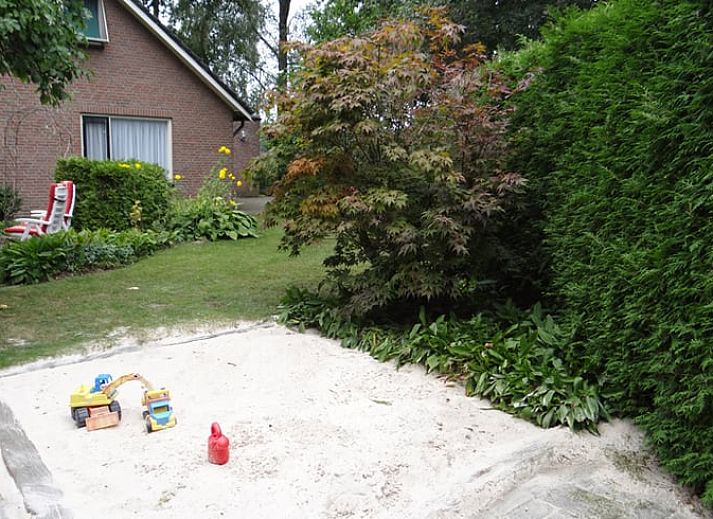 Dining room with wooden table and chairs in vacation home Hezingen, Twente, with garden view.