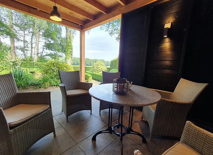 Dining room with wooden table and chairs in vacation home Hezingen, Twente, with garden view.