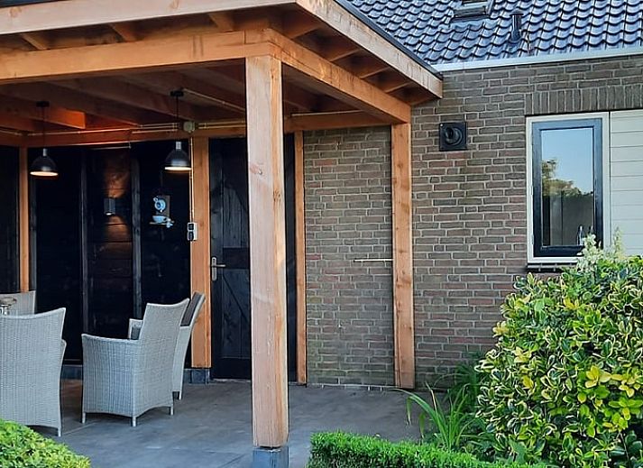 Dining room with wooden table and chairs in vacation home Hezingen, Twente, with garden view.