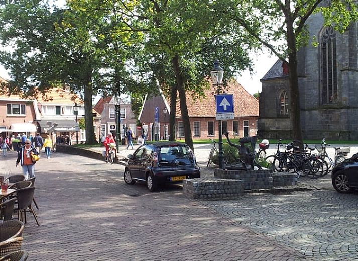 Dining room with wooden table and chairs in vacation home Hezingen, Twente, with garden view.