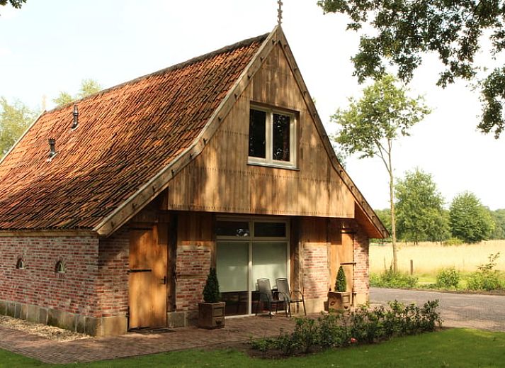 Cottage in Hezingen, ein charmantes Ferienhaus in Twente, Overijssel mit rustikaler Fassade und gruener Umgebung.