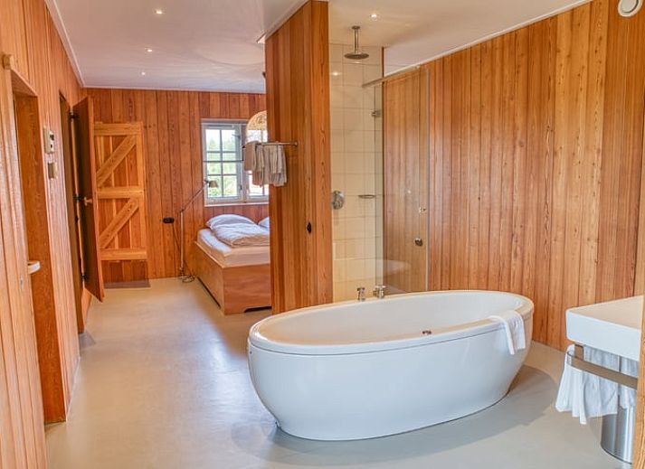 Attractive bedroom in cottage in Beuningen, Twente with wooden interior and modern bathroom.