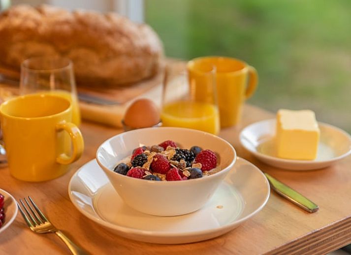Cozy living room in Cottage in Beuningen, Twente with colorful cushions and wooden furniture.