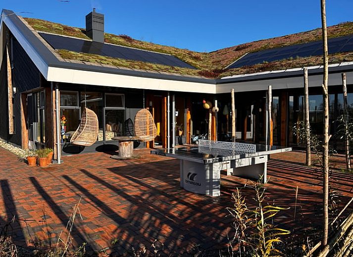 Ferienhaus in Rijssen mit gruenem Dach und bunten Blumen in Twente, Overijssel.