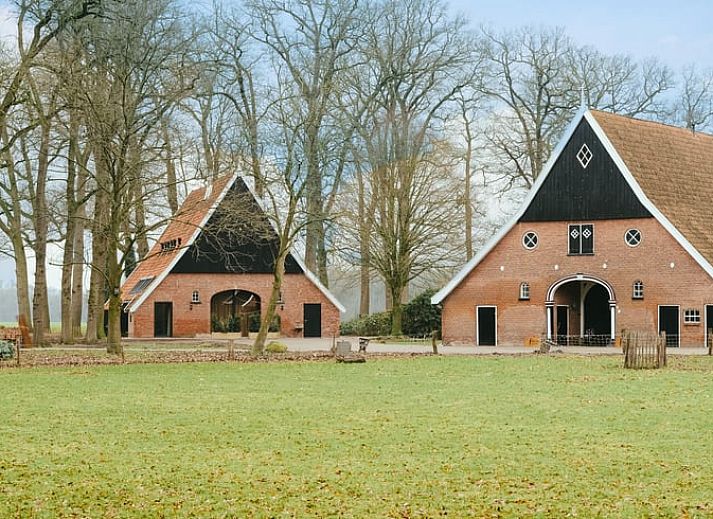 Exterior view of Cottage in Rossum, vacation home in Twente, Overijssel, surrounded by flowers and trees.