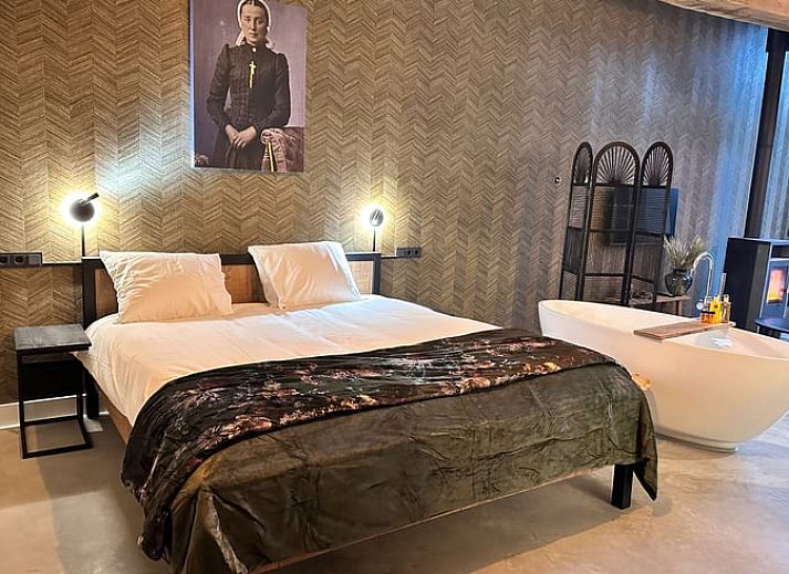 Gemuetliche Details im Ferienhaus in Rossum, Twente, mit weichen orangefarbenen Kissen auf dem Bett.