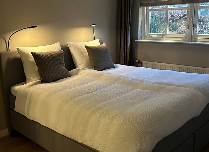 Cottage in Rossum, ein Ferienhaus in Twente, Overijssel, umgeben von einem gruenen Garten und einem Waldgebiet.