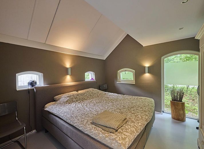 Design Lodge Twente Ferienhaus mit Terrasse und Liegestuehlen in Haaksbergen, Overijssel, umgeben von gruener Natur.