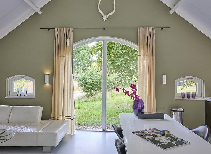 Design Lodge Twente Ferienhaus mit Terrasse und Liegestuehlen in Haaksbergen, Overijssel, umgeben von gruener Natur.