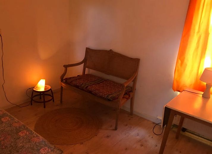 Terras van Huisje in Diepenheim, vakantieaccommodatie in Twente met groen uitzicht en spelende hond.