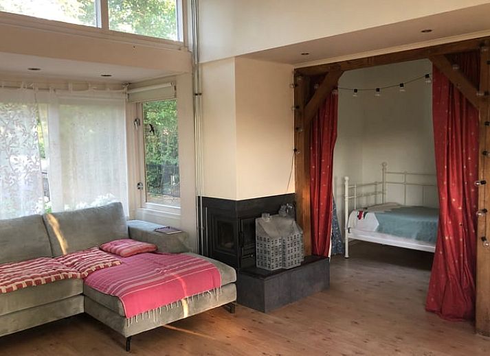 Terras van Huisje in Diepenheim, vakantieaccommodatie in Twente met groen uitzicht en spelende hond.