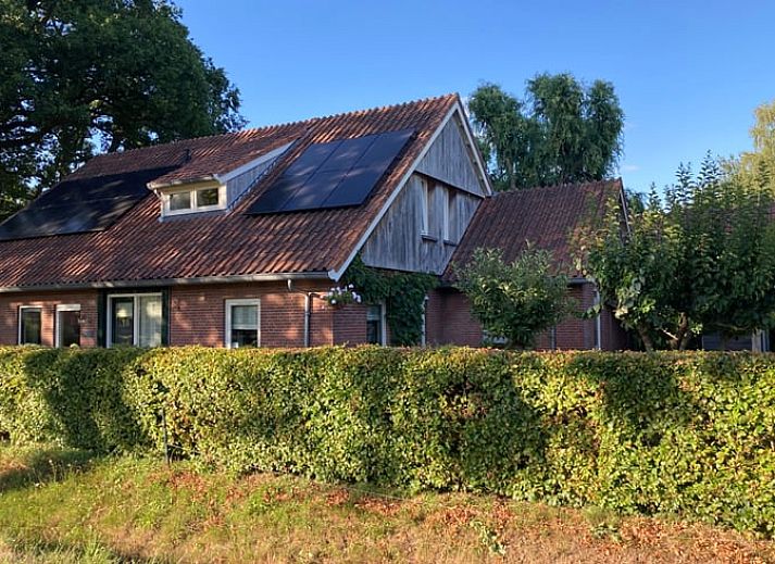 Vakantiehuis in Oldenzaal, Twente, met charmante houten gevel en rode dakpannen, omringd door weelderige natuur.