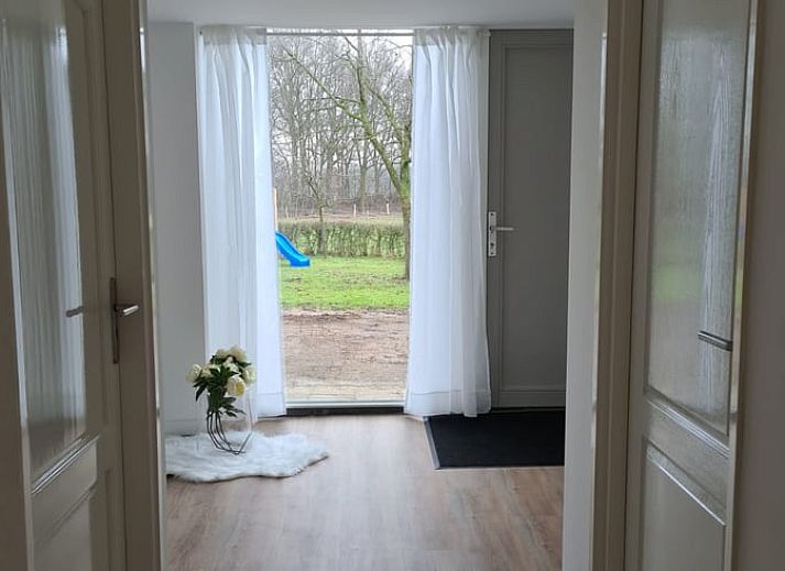 Ontspan in de tuin van Vakantiehuisje in Markelo, gelegen in het groene Twente, Overijssel, met kleurrijke bloemen en ligstoelen.