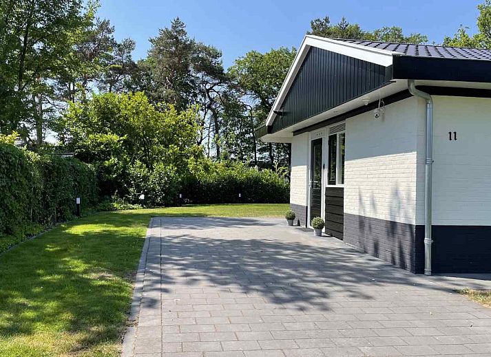 DG630 Ferienhaus in Denekamp, Twente mit sonniger Terrasse und Sonnenschirm auf gruenem Rasen.