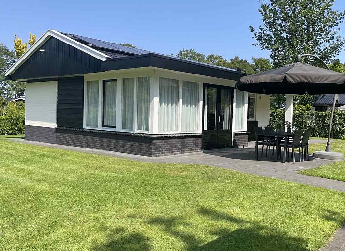 Geraeumige Terrasse mit Sonnenschirm im Ferienhaus DG630 in Denekamp, Twente, umgeben von viel Gruen.