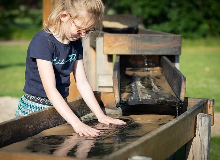 Schaukelstuhl auf der Terrasse des Ferienhauses in Buurse, Twente, Overijssel mit gruener Umgebung.