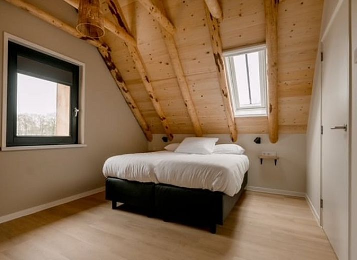Interior of Huisje in Agelo, vacation home in Twente, Overijssel with wooden beams and artwork on the wall.