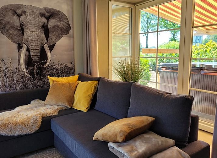 Gemuetliches Wohnzimmer im Ferienhaus in Lonneker, Twente, mit bequemer Sitzecke und stimmungsvoller Beleuchtung.