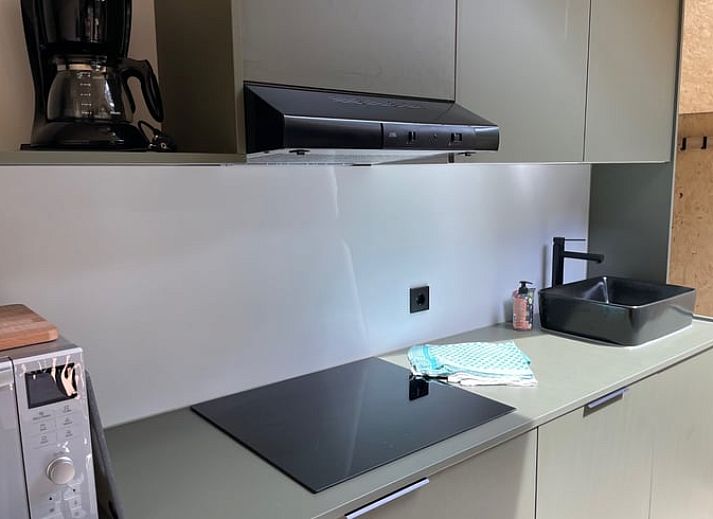 Gemuetlicher Innenbereich des Ferienhauses in Holten, Overijssel, mit bequemen Stuehlen und Blick auf die Landschaft von Salland.