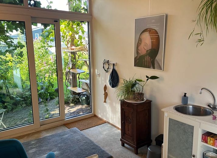 Aussenterrasse des Ferienhauses in Olst, Overijssel mit gruener Umgebung und blauen Gartenmoebeln.