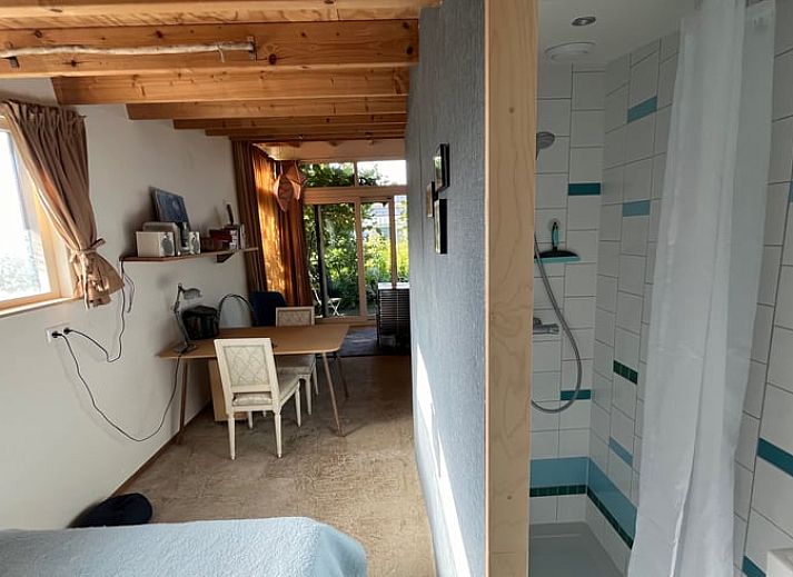 Aussenterrasse des Ferienhauses in Olst, Overijssel mit gruener Umgebung und blauen Gartenmoebeln.