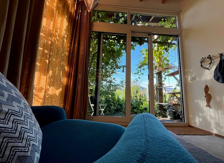 Aussenterrasse des Ferienhauses in Olst, Overijssel mit gruener Umgebung und blauen Gartenmoebeln.